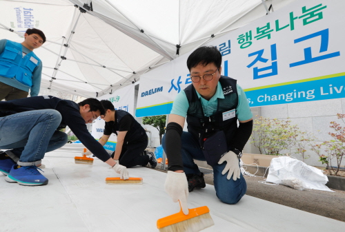 15일 대림산업 박상신 대표(우측 첫번째)가 서울시 용산구에 위치한 해오름빌에서 도배작업에 사용할 벽지에 풀칠을 하고 있다. [사진=대림산업]