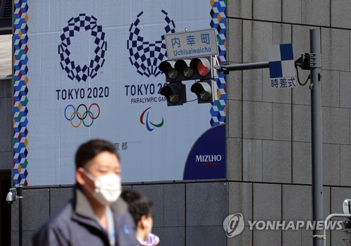 마스크를 쓴 남성이 지난 9일 오후 도쿄 올림픽·패럴림픽 홍보물이 설치된 일본 도쿄도(東京都) 지요다(千代田)구의 한 사거리를 지나가고 있다. [사진=연합뉴스]