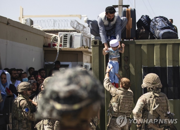 카불 공항서 영국군에 아이 건네는 아프간 남성. [사진출처=연합뉴스]
