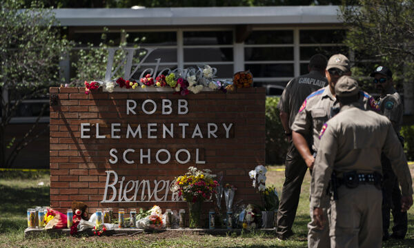 지난 25일(현지시간) 미국 텍사스주 소도시 유밸디의 롭 초등학교 앞 교명 표지판 주변에 총기난사 희생자들을 추모하는 꽃과 양초들이 놓여 있다. [유밸디=AP연합뉴스]