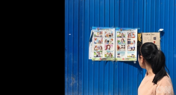 중국 베이징의 한 여성이 시내 곳곳에 게시된 “잘생긴 외국인과의 데이트할 때  주의하라”는 내용이 담긴 만화 형식의 포스터를 보며 지나가고 있다. [CNN 홈페이지 캡처]