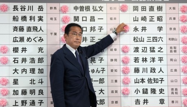 기시다 후미오('田文雄) 일본 총리 겸 자민당 총재가 참의원 선거 승리를 알리는 자민당 후보의 이름에 빨간 장미를 꽂고 있다.[출처=연합]