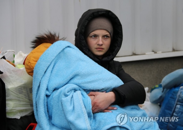 폴란드 코르쵸바 국경검문소 인근 임시 난민수용시설에서 한 우크라이나 여성이 바닥에 앉은 채 잠든 아기를 안고 있다. [사진=연합뉴스]
