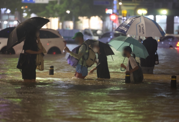 8일 밤 서울 강남구 대치역 인근 도로와 인도가 물에 잠기면서 차량과 보행자들이 통행하는 데 불편을 겪고 있다. [출처=연합]