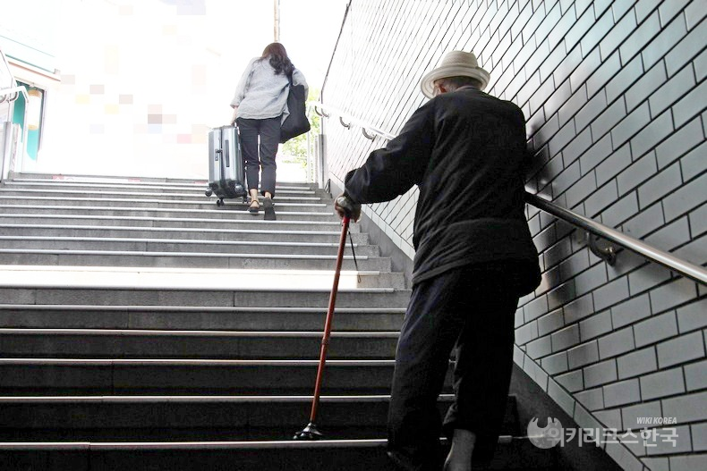 지하철 1호선 종로5가역에서 여행용 가방을 든 20대 여성과 80대 노인이 난간을 잡고 힘겹게 계단을 오르고 있다. [출처=정수남 기자]
