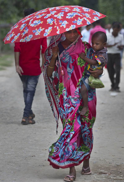 인도에서는 소수 종교 집단에 속하는, 아이를 안은 한 무슬림 여성이 국가시민등록부(NRC) 인증센터를 향해 걷고 있는 모습 [사진=연합뉴스]