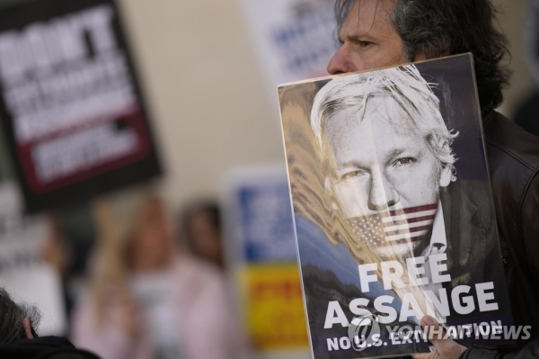 Wikileaks founder Julian Assange supporters hold placards as they gather outside Westminster Magistrates court in London on Wednesday.    /AP=Yonhap