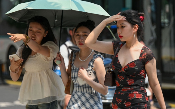 지난 달 29일, 여성들이 중국 상하이 한 거리에서 우산과 손으로 햇빛을 가리고 걸어가고 있다. 상하이는 이날 낮 기온이 36.7도까지 치솟으면서 100년 만에 최고 5월 기온을 기록했다. [사진 = 연합뉴스]