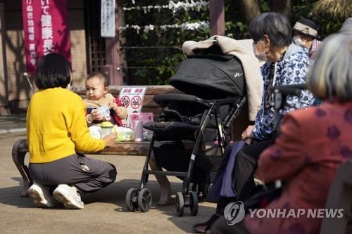 일본 도쿄에서 아이를 돌보는 여성과 이를 지켜보는 노인들 [사진 = 연합뉴스]