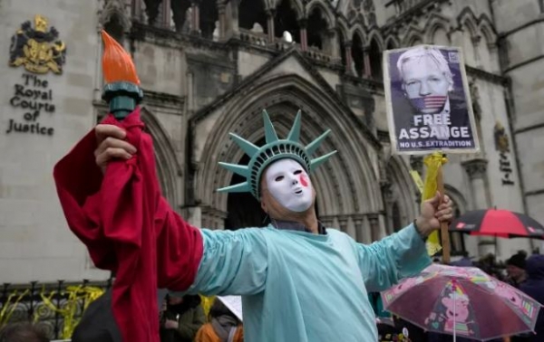 A protester stands outside the Royal Courts of Justice in London, Wednesday, February 21, 2024., where Julian Assange's lawyers are on their final UK legal challenge to stop the WikiLeaks founder from being sent to the United States to face spying charges [AP Yonhap]