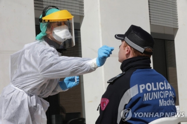 [지난 25일 스페인 마드리드에서 한 경찰관이 코로나19 검사를 받는 모습. / 사진=연합뉴스]