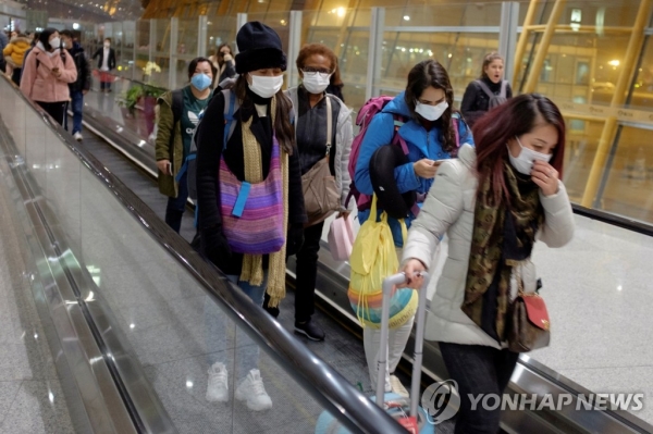 25일 중국 베이징 공항에 도착한 여행객들이 마스크를 쓴 채 에스컬레이터를 타고 이동하고 있다 [사진=연합]