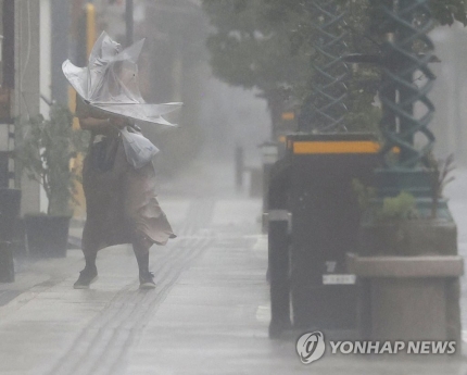(미야자키 교도=연합뉴스) 제14호 태풍 '난마돌'이 북상하는 가운데 18일 오후 일본 미야자키현 미야자키시에서 우산을 든 사람이 강한 비바람을 맞으며 이동하고 있다.