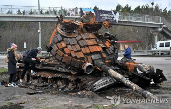 파괴된 러시아군 탱크를 살피는 우크라이나 주민들 [AFP=연합뉴스]