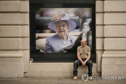 엘리자베스 2세 여왕 초상화 앞에 앉아 있는 영국 시민. [AP=연합뉴스]