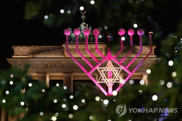 지난 2017년 12월 12일, 독일 베를린에서 유대교의 명절 '하누카'를 맞아 거대한 촛대 '미노라'가 브란덴부르크 문 앞에서 밝게 빛나고 있다. 유대교의 빛의 축제로도 불리는 하누카는 전 세계 유대인들에게 가장 중요한 명절 중 하나로 알려져 있다. [사진 = 연합뉴스]