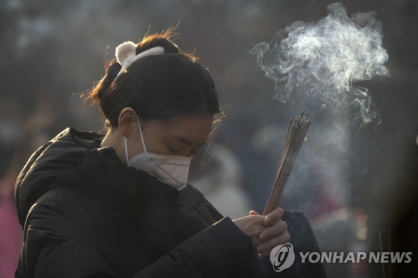 지난 1월 중국 베이징 융허궁에서 향을 피우며 기도하는 한 여성의 모습 [사진 = 연합뉴스]
