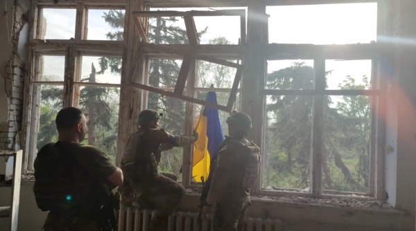 우크라이나 군인들이 11일(현지시간) 동남부 도네츠크주 블라호다트네를 탈환한 뒤 건물에 자국 국기를 게양하고 있다. 최근 대반격에 나선 우크라이나는 도네츠크주의 마카리우카, 블라호다트네, 네스쿠치네 마을을 되찾았다고 이날 밝혔다.[출처=로이터/연합]