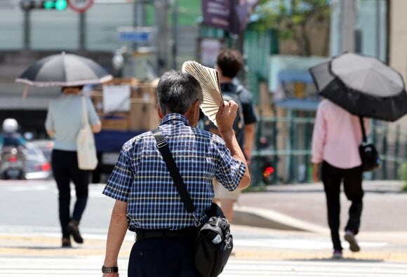 한 시민이 지난달 31일 부산진구 부산시민공원 앞에서 부채를 들고 햇볕을 가리고 있다