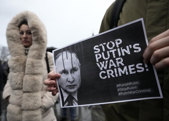 지난해 12월 24일 세르비아 베오그라드에서 시위대가 블라디미르 푸틴 대통령의 사진과 함께 "푸틴의 전쟁범죄를 멈춰라"는 문구의 플래카드를 들고 우크라이나 전쟁을 반대하는 시위를 벌이고 있다. [사진 = 연합뉴스]
