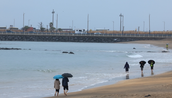 지난 11일 오후 제주시 이호해수욕장을 찾은 이들이 우산을 쓰고 산책하고 있다. [출처=연합]